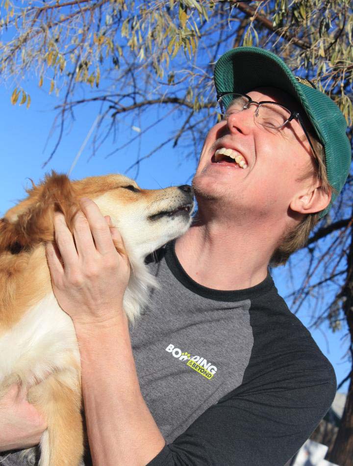 Boarding & Beyond male employee laughing with a dog